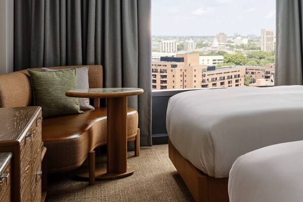 Ein Hotelzimmer mit einem großen Bett, einer Couch, einem kleinen Tisch und Blick auf die Stadt.