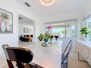 A dining area with a table, chairs, and a potted plant. - Barefoot Bungalow - Stroll to beach (Treasure Island)