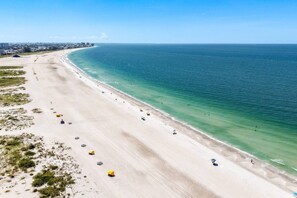 Ein Strand mit freiem Blick auf das Meer, einem sandigen Ufer und einigen Sonnenschirmen.