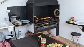 Een keuken met een houtgestookte oven, een tafel met eten en een groene mat.