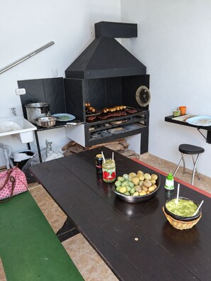 Eine Küche mit Holzofen, einem Tisch mit Speisen und einer grünen Matte.