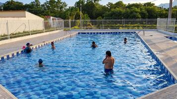 A swimming pool with a tiled deck and a metal fence.