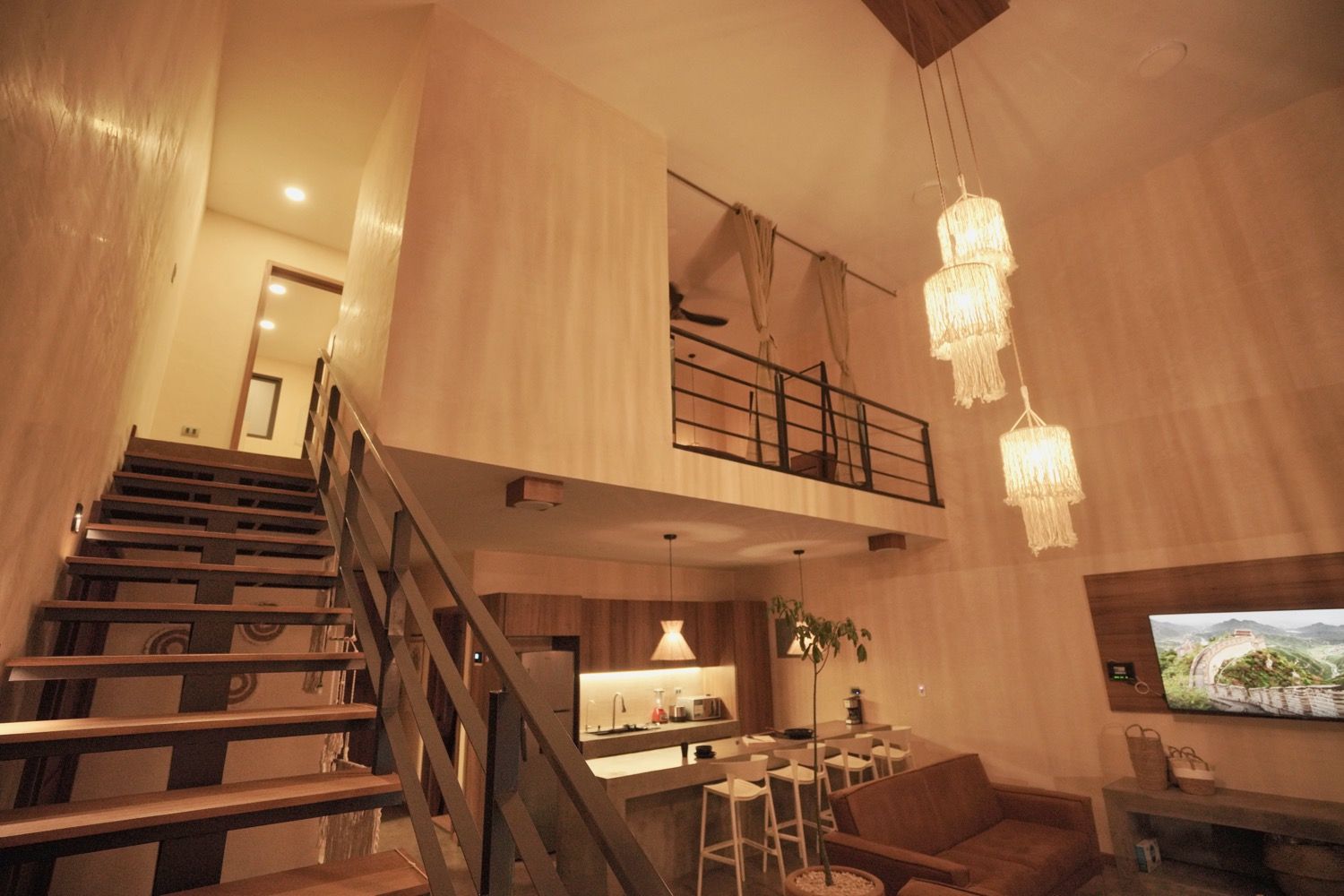 A spacious living area with a staircase, a kitchen, and a dining area.