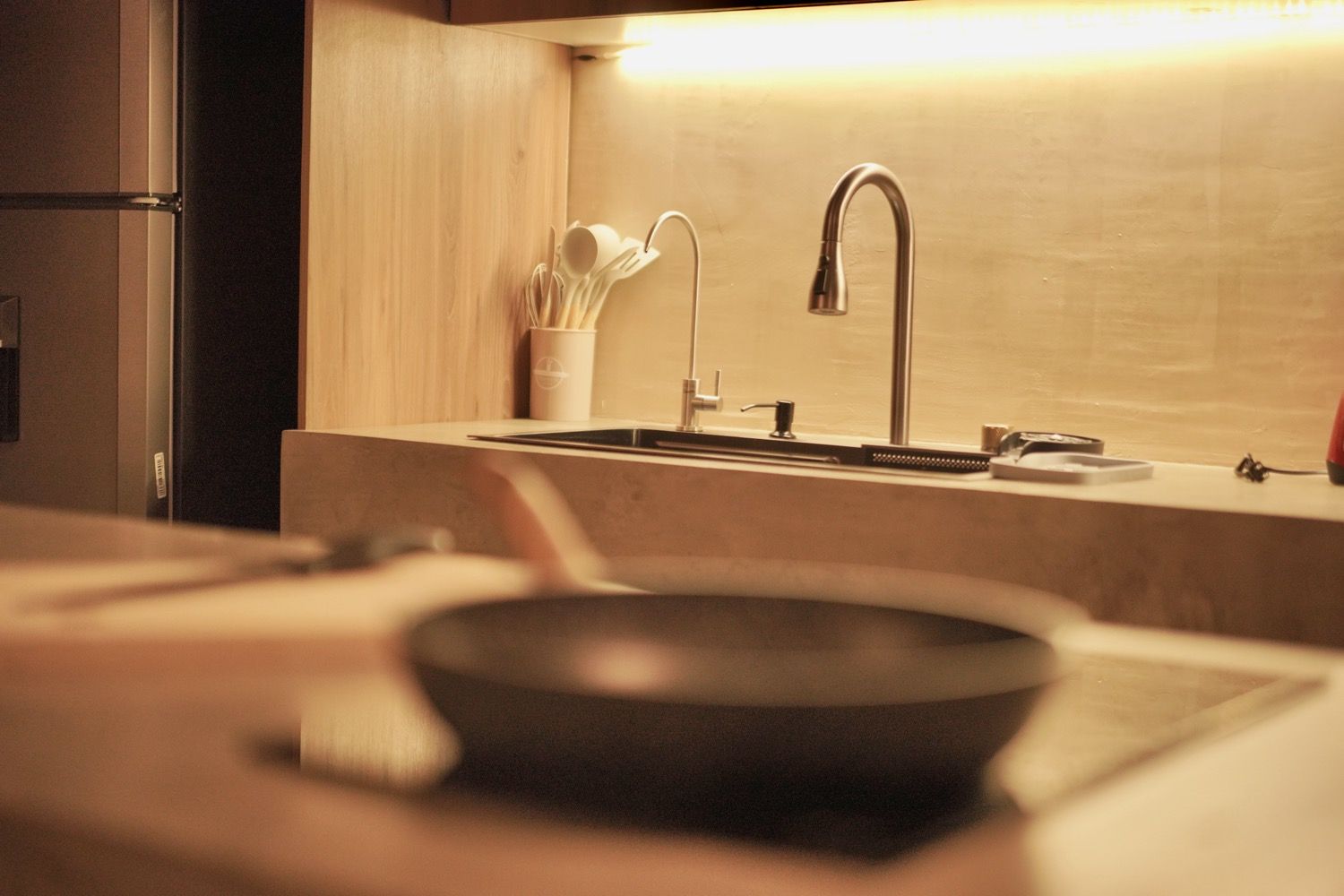 A kitchen with a modern faucet, a sink, and a pan on the countertop.