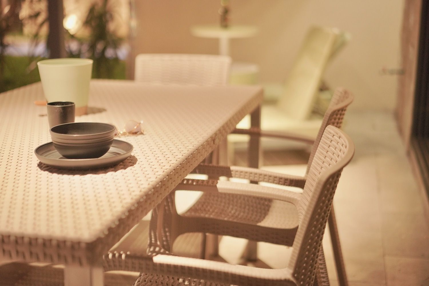 Uma mesa de jantar de vime com uma tigela e uma chávena, rodeada por cadeiras de vime.