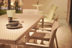 A wicker dining table with a bowl and a cup on it, surrounded by wicker chairs.