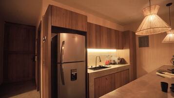 Cozinha moderna com armários de madeira, geladeira de aço inoxidável, pia embutida e luminária pendente.