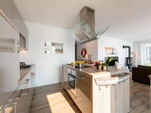 Een moderne keuken met een centraal eiland, een inbouwoven en roestvrijstalen apparatuur.