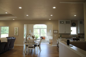 A spacious living area with a dining table, chairs, a sofa, and a kitchen area with cabinets and a sink.