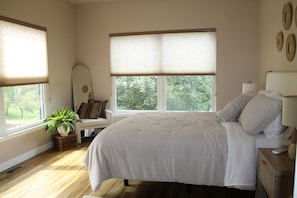 A bedroom with a bed, bedside tables, a potted plant, and a window with blinds. - Enjoyable 5-bedroom house with AC in welcoming Wellman (Wellman)