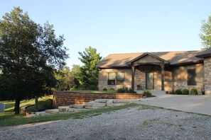 A residential house with a stone facade, a front porch, and a driveway. - Enjoyable 5-bedroom house with AC in welcoming Wellman (Wellman)