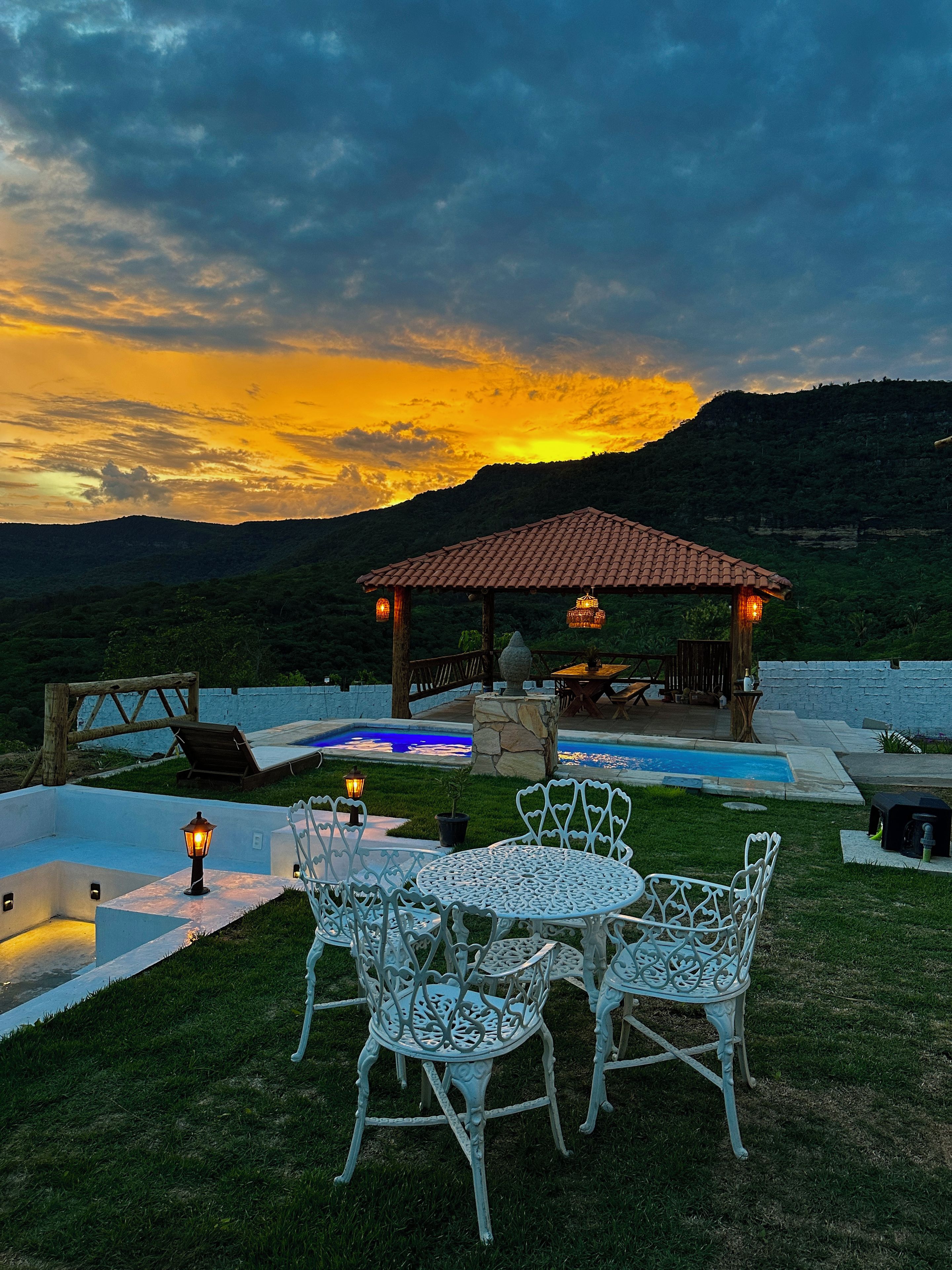 A patio with outdoor furniture, a swimming pool, and a gazebo with a tiled roof.