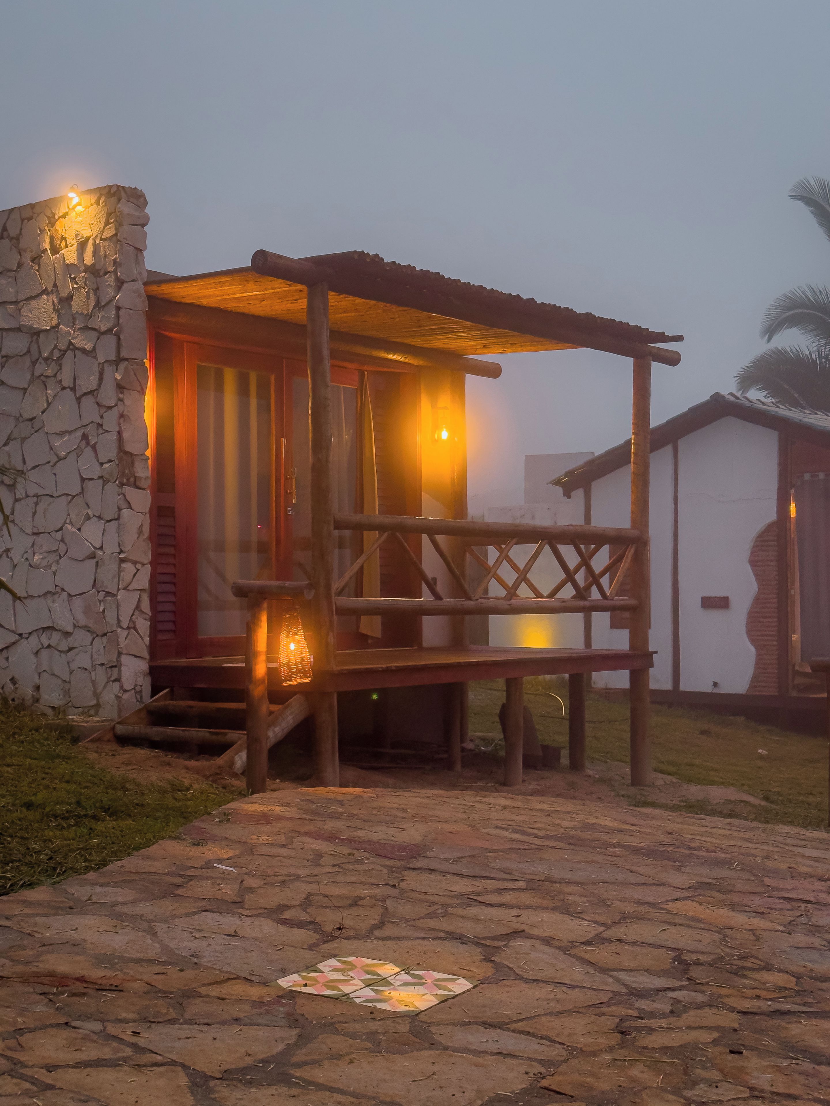 A rustic wooden structure with a stone wall, a wooden porch, and a small table.