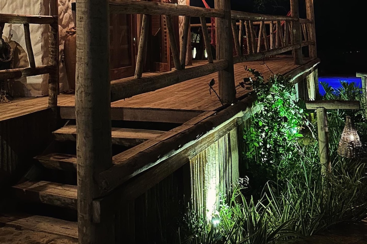 A rustic wooden building with a balcony, wooden railings, and hanging light fixtures.