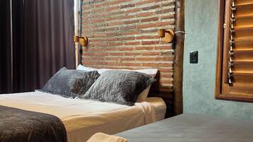 A hotel room with a bed, pillows, a wooden wall with a paddle, and a window with blinds.
