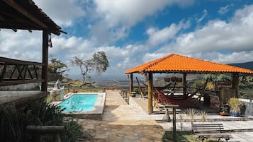Um caminho de pedra leva a uma piscina e área de estar externa, com vista para a paisagem.