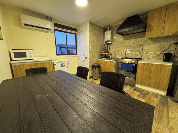 A modern kitchen with a dining table, built-in appliances, and a view through the window.