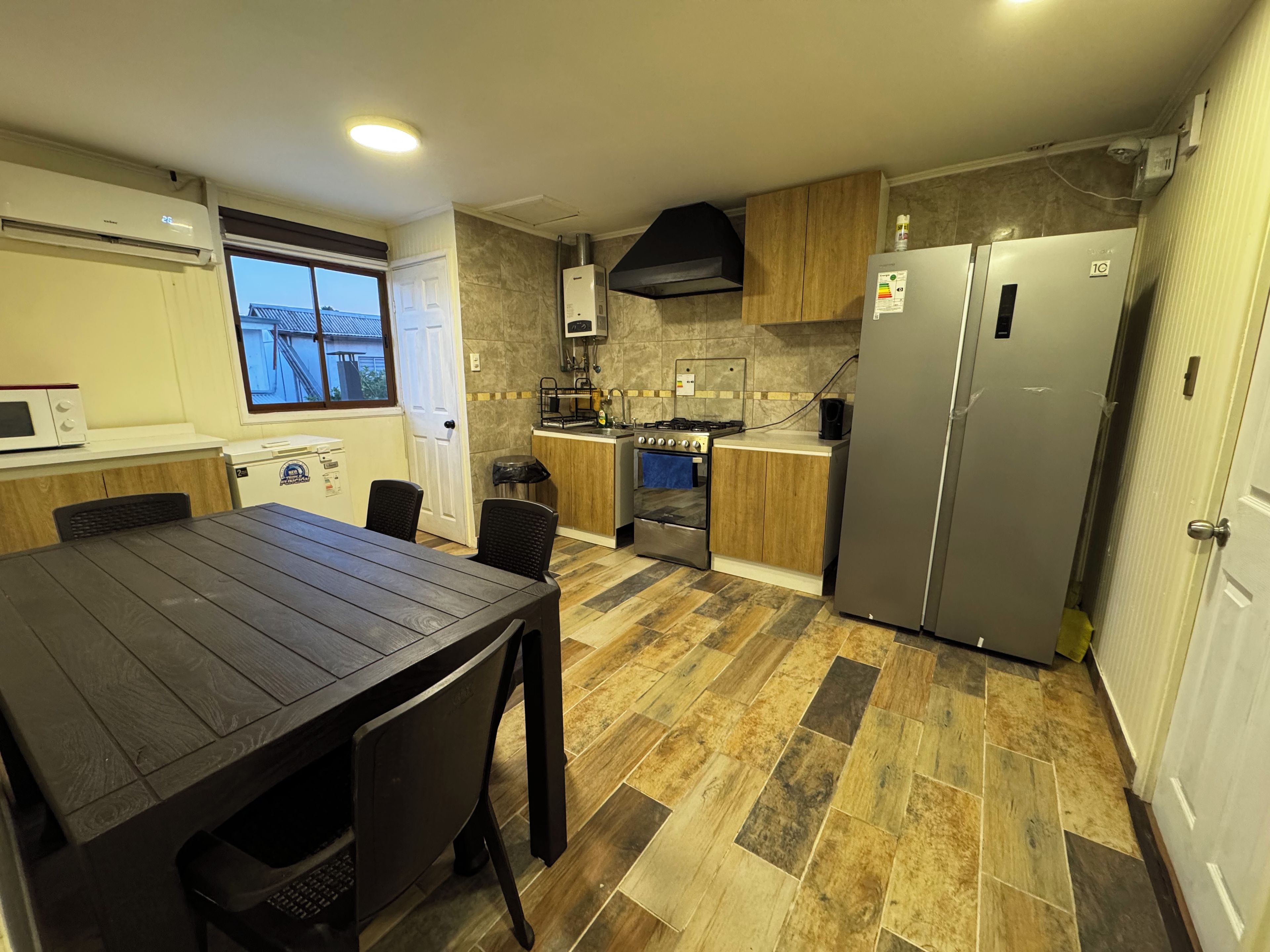 A modern kitchen with a dining table, built-in appliances, and a view of the outside.