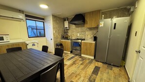 Une cuisine moderne avec une table à manger, des appareils électroménagers intégrés et une vue sur l’extérieur.