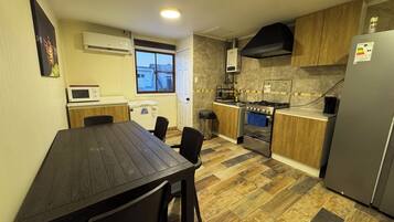 Een praktische keuken met een eettafel, stoelen, een magnetron, een fornuis en een koelkast.