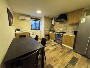 A compact kitchen with a dining table, chairs, a microwave, a stove, and a refrigerator.