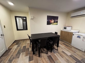 A compact kitchen with a dining table, chairs, a microwave, and a refrigerator.