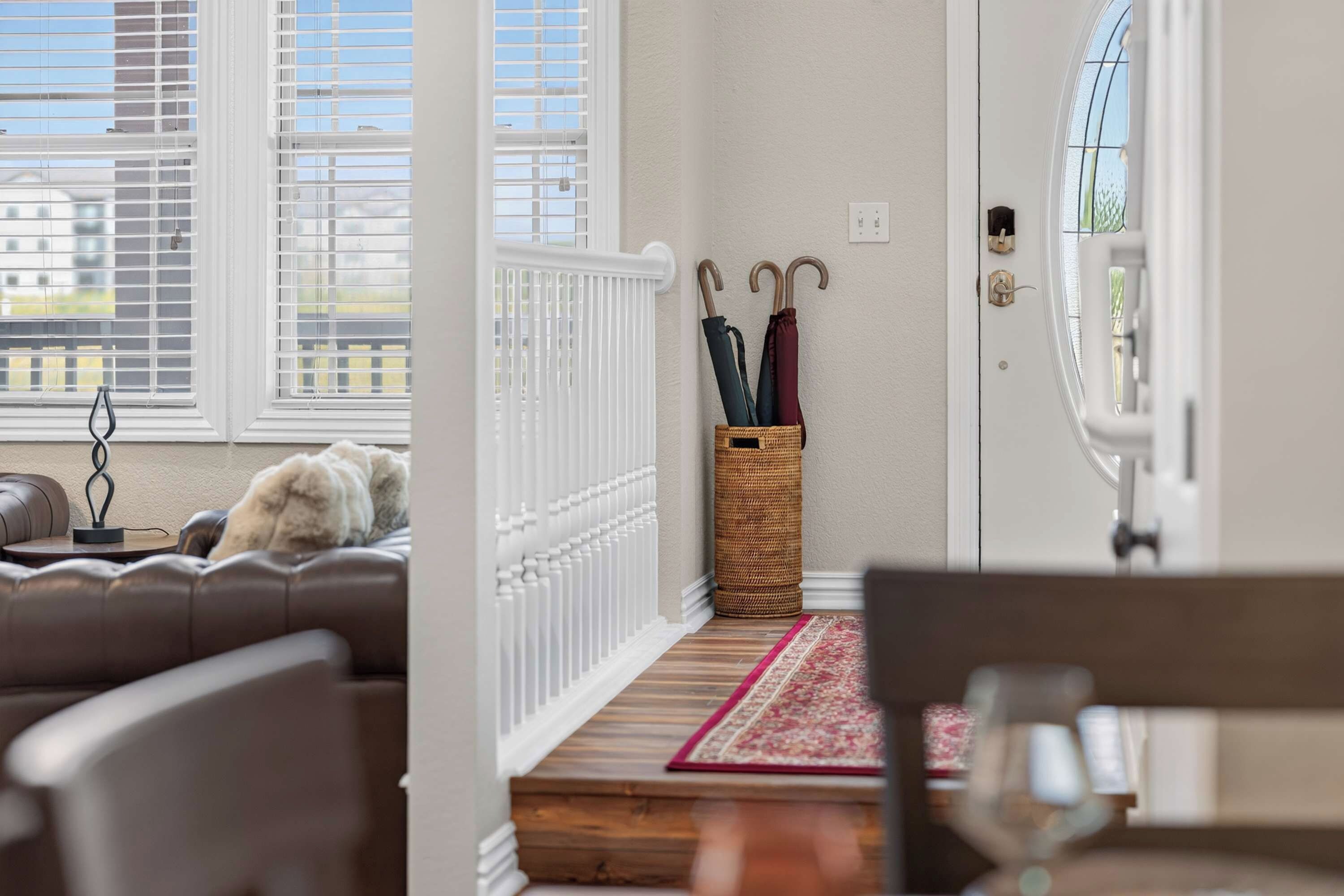 A cozy living room with a sofa, a dog, a wicker basket with umbrellas, and a view through the window.
