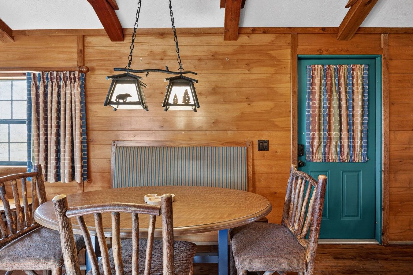 Un interior de madera con una mesa redonda, sillas y una puerta color turquesa.