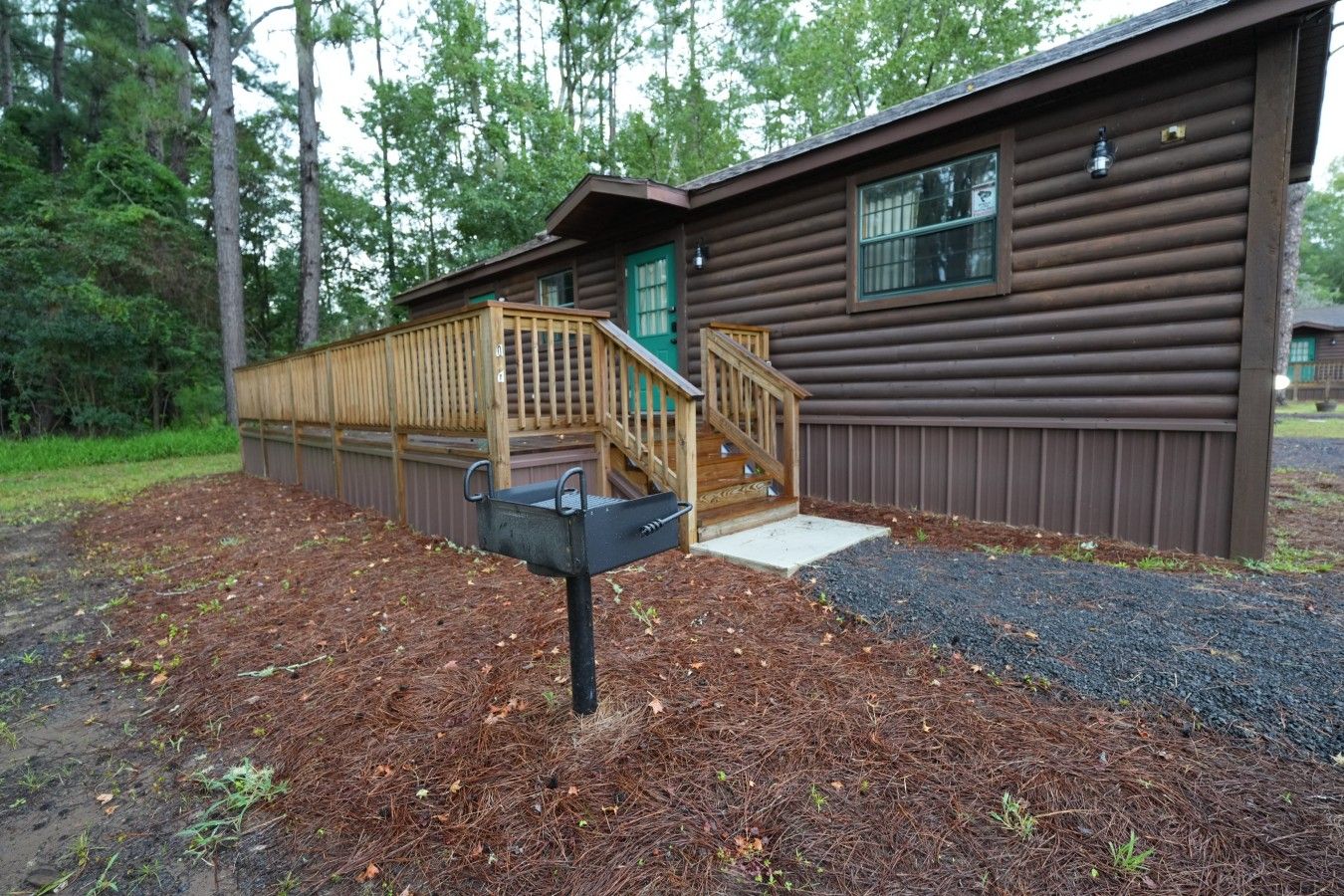 A wooden cabin with a wooden deck and a mailbox.