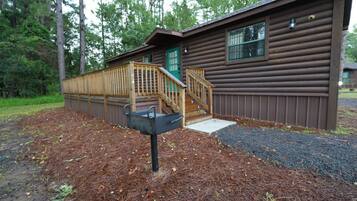 A wooden cabin with a wooden deck and a mailbox.