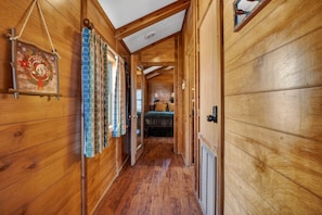 A wooden hallway with a bed at the end, a door with a lock, and a sign on the wall.