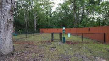 A fenced outdoor area with a wooden fence, a signpost, and a tree.