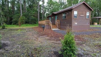 A cabin with a wooden deck, a small porch, and a mailbox.