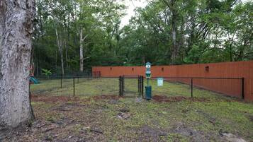 A fenced outdoor area with a wooden fence, a signpost, and a tree.