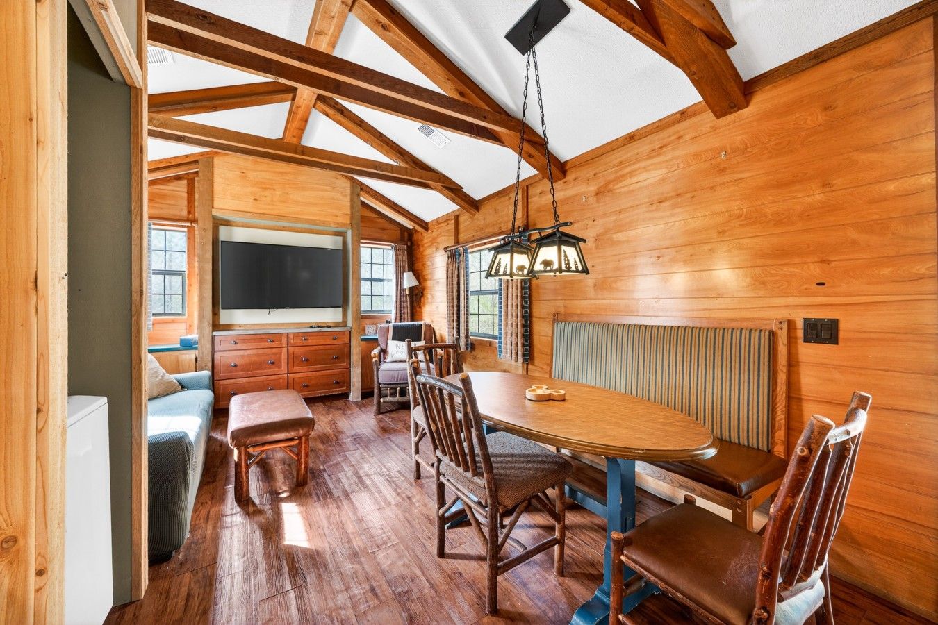 A wooden interior with a dining area, a television, and a window.