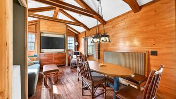 A wooden interior with a dining area, a television, and a window.