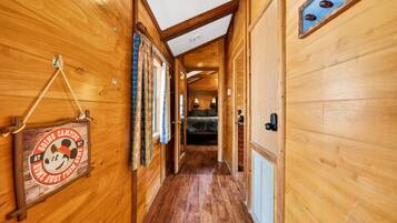 Ein Holzboden-Flur mit einem Schild links, einem Bett im Hintergrund und einer Tür rechts.