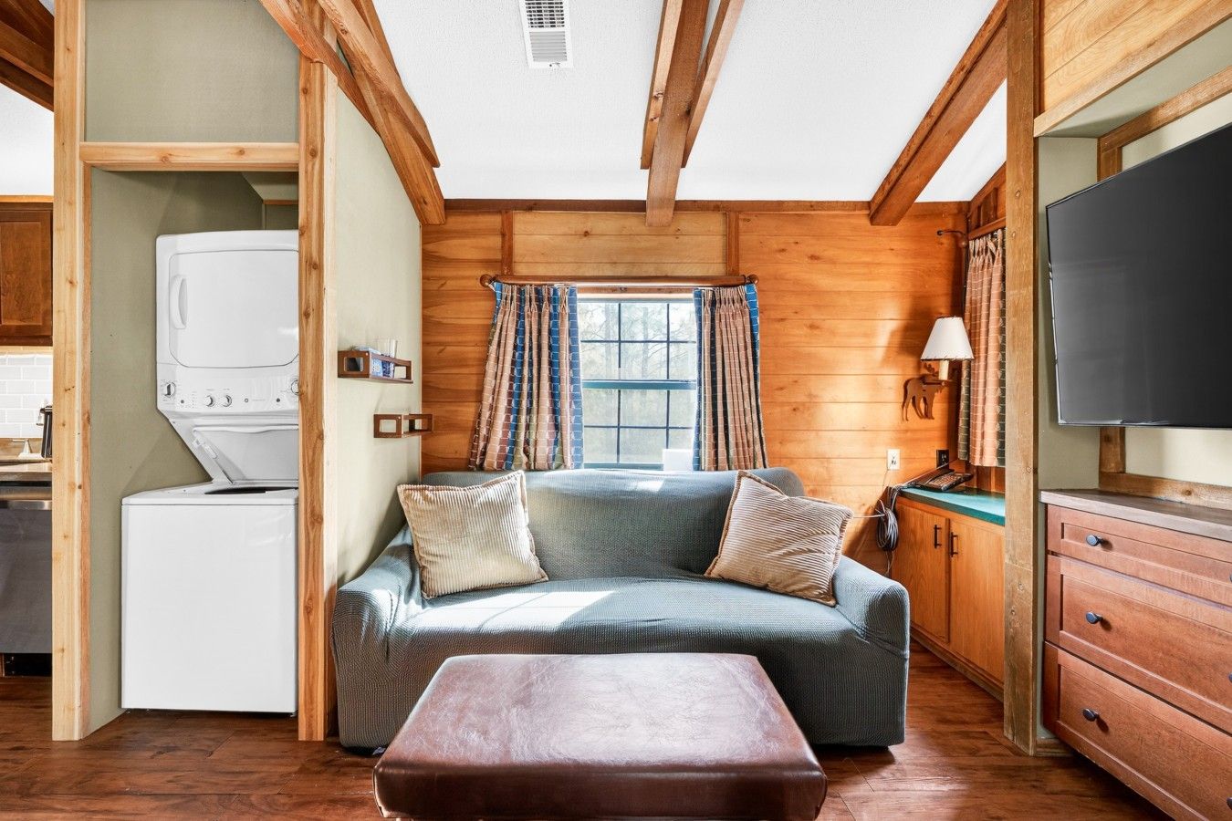 Ein gemütliches Blockhauss-Interieur mit einer Couch, einem Fernseher und einer Waschmaschine.