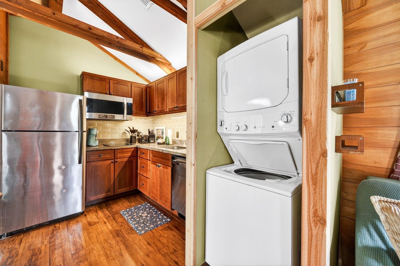 Une cuisine compacte avec des meubles en bois, un réfrigérateur en acier inoxydable, un four à micro-ondes et un lave-linge.