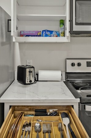 A kitchen with a toaster, a roll of paper towels, and a drawer with utensils. - Vintage Farmhouse Charm - 8 Min to Duke and DT (Durham)