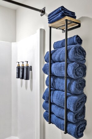 A bathroom with a towel rack holding multiple towels and a shelf with toiletries. - Vintage Farmhouse Charm - 8 Min to Duke and DT (Durham)