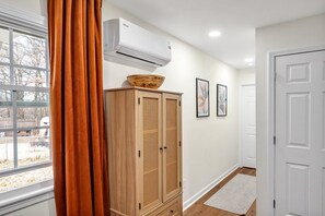 A hallway with a wooden wardrobe, an air conditioning unit, a white door, and a window with curtains. - 8 Min to Duke + DT | Free Parking + Wi-Fi (Durham)