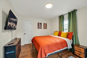 A bedroom with a bed, a television, a dresser, and a door. - 8 Min to Duke + DT | Free Parking + Wi-Fi (Durham)