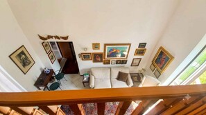 A high-ceiling living room with a sofa, a coffee table, and various framed pictures on the walls. - Holiday flat with internet (Belgirate)