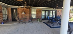 Un patio al aire libre con muros de ladrillo, una zona de estar cubierta y ventiladores de techo.