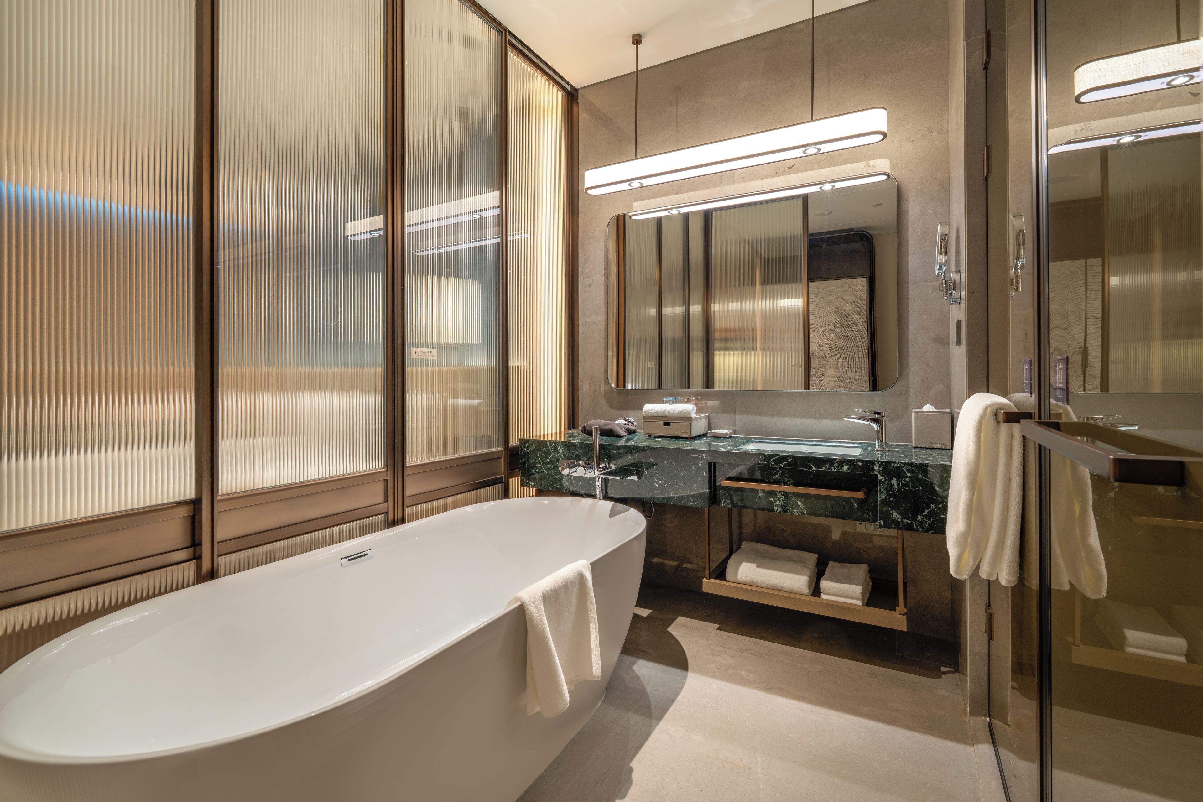 A modern bathroom with a freestanding bathtub, a vanity with a mirror, and a glass-enclosed shower area.