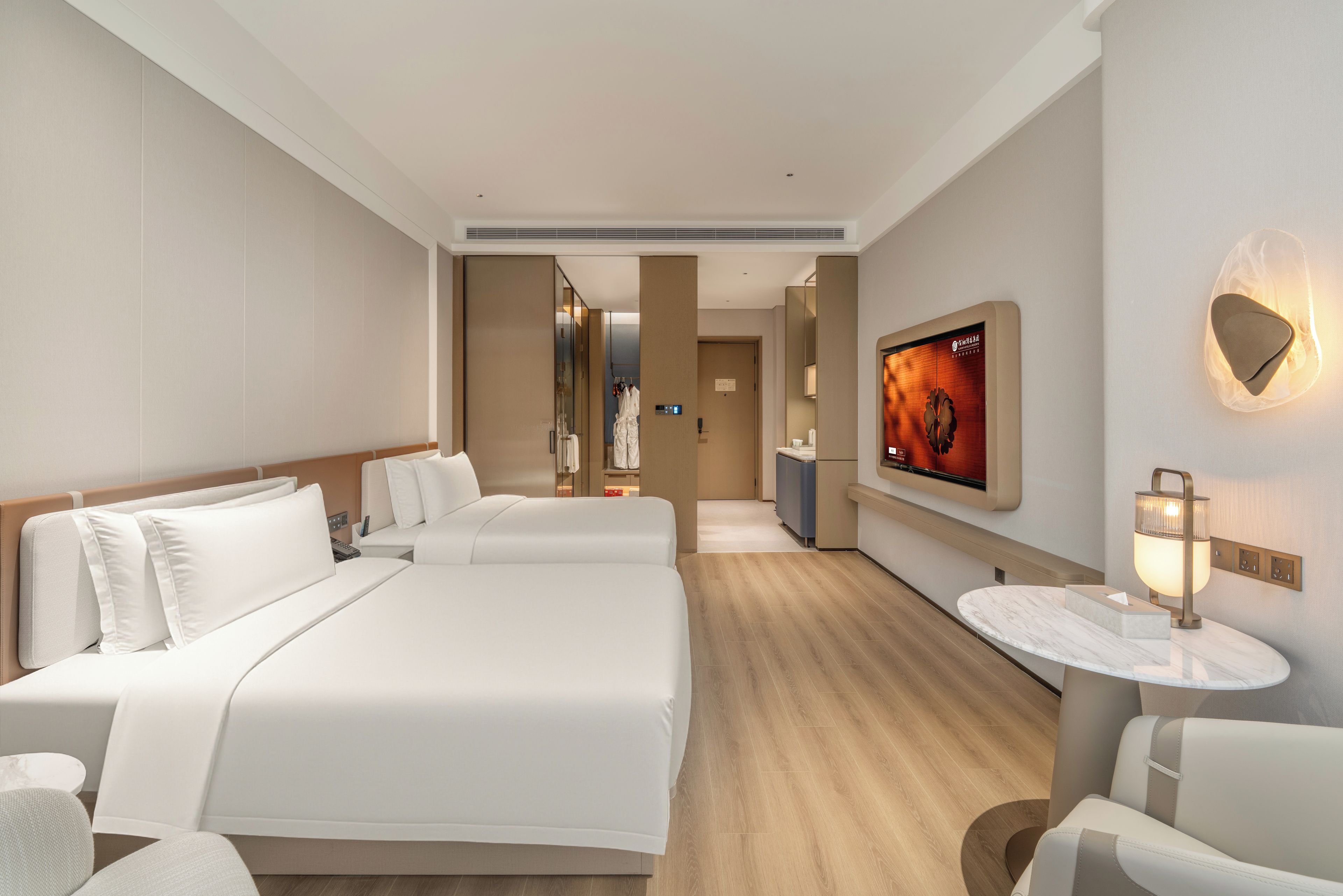 Une chambre d’hôtel avec un grand lit, un coin salon avec une table et un téléviseur fixé au mur.