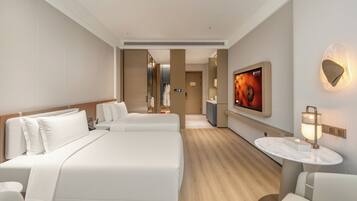 Une chambre d’hôtel avec un grand lit, un coin salon avec une table et un téléviseur fixé au mur.