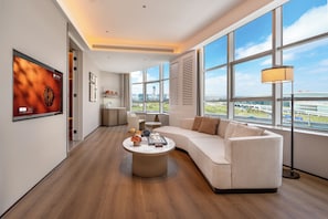 Una sala de estar moderna con un ventanal grande, un sofá, una mesa de centro y un televisor montado en la pared.
