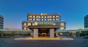 A modern hotel with a curved facade, illuminated signage, and a spacious entrance area.
